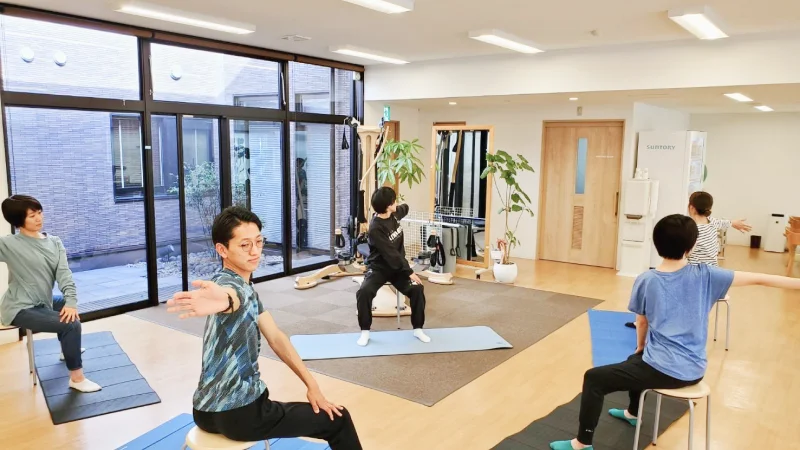 マットを引いて運動する利用者と指導する理学療法士