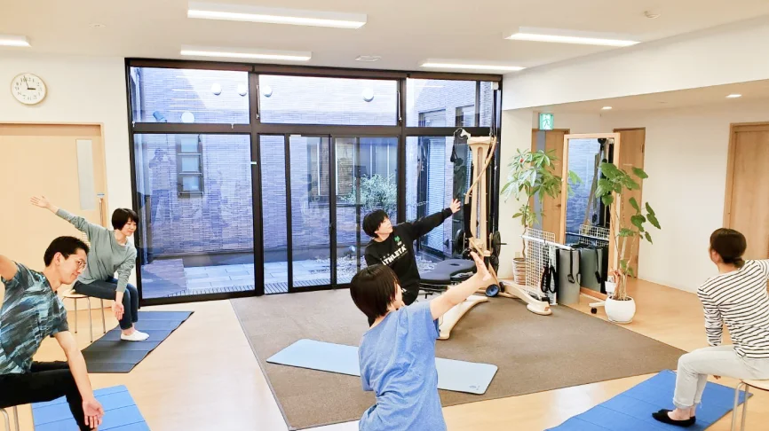 マットの上で運動する利用者とインストラクター