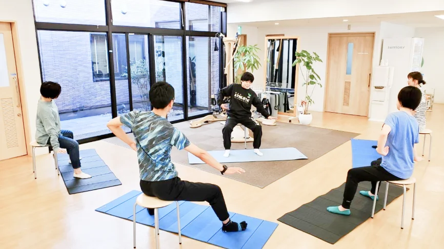 転倒予防トレーニングをする利用者たちと指導する理学療法士