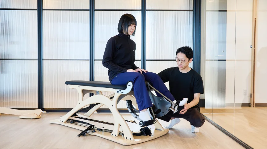 柔軟性と筋力を同時に向上させるトレーニングをする女性とサポートする理学療法士