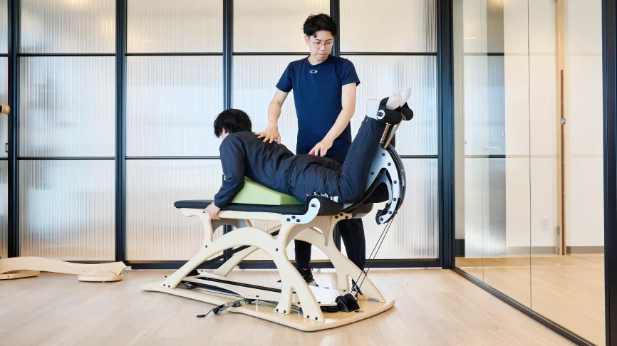 軸を強化する女性とサポートする理学療法士