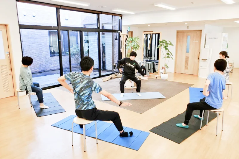 プログラムに沿って、産後骨盤矯正のレッスンをする利用者と指導する理学療法士