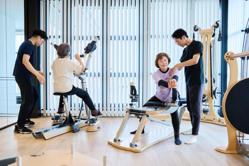 ジャイロトニック®のマシンによるパーソナルトレーニングをする利用者たちとサポートする理学療法士