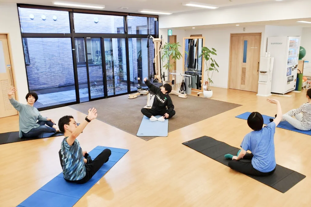 マットを引いて運動する利用者とインストラクター