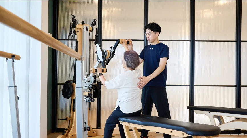 麻痺側の運動改善トレーニングをする女性とサポートする理学療法士