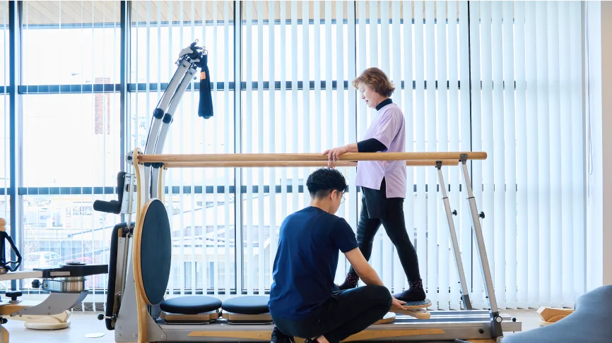 姿勢改善のための運動をする利用者とサポートする理学療法士