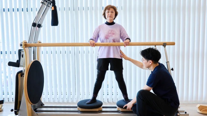 無理なく運動している年配の女性とサポートする理学療法士